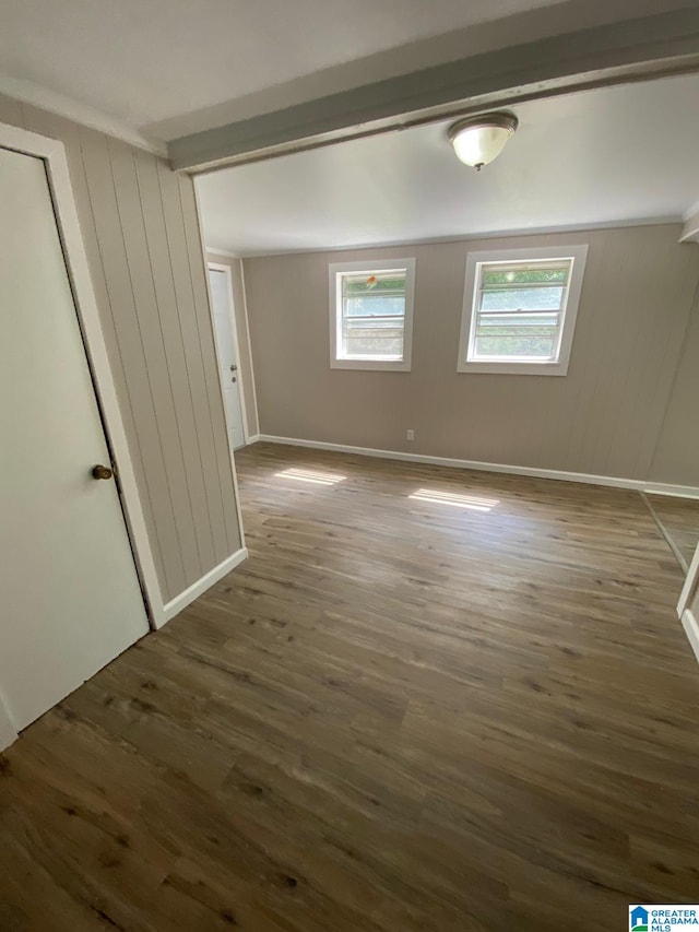 unfurnished bedroom featuring dark wood-type flooring, wooden walls, and a closet