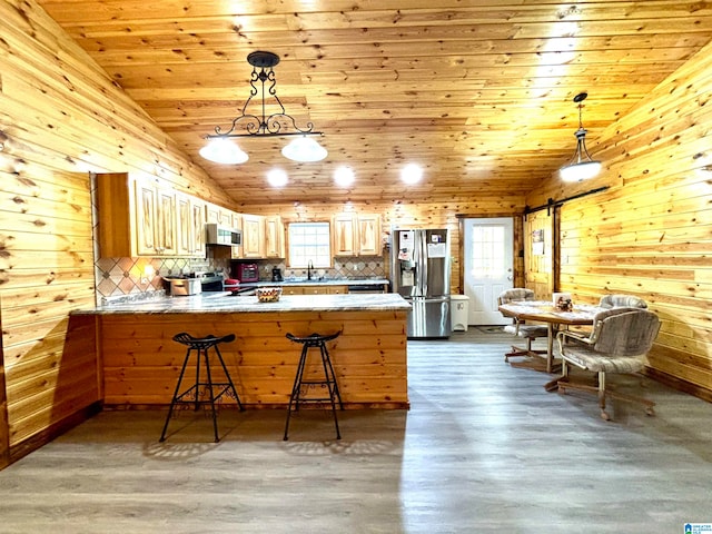 kitchen with wood walls, kitchen peninsula, appliances with stainless steel finishes, and tasteful backsplash