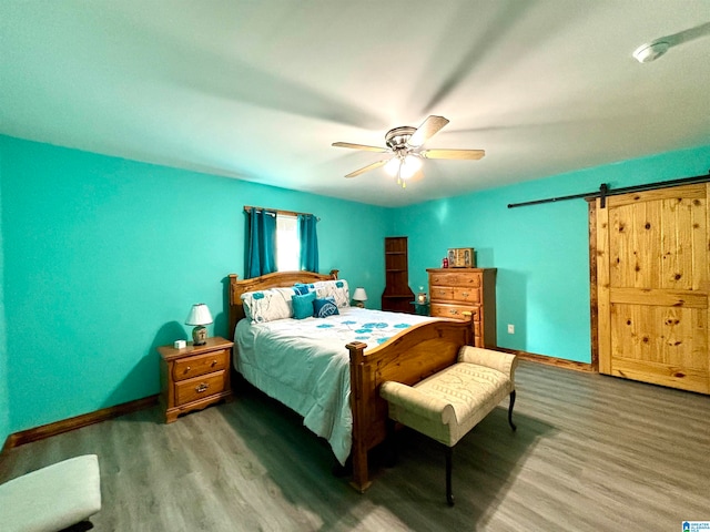 bedroom featuring a barn door, ceiling fan, and hardwood / wood-style floors