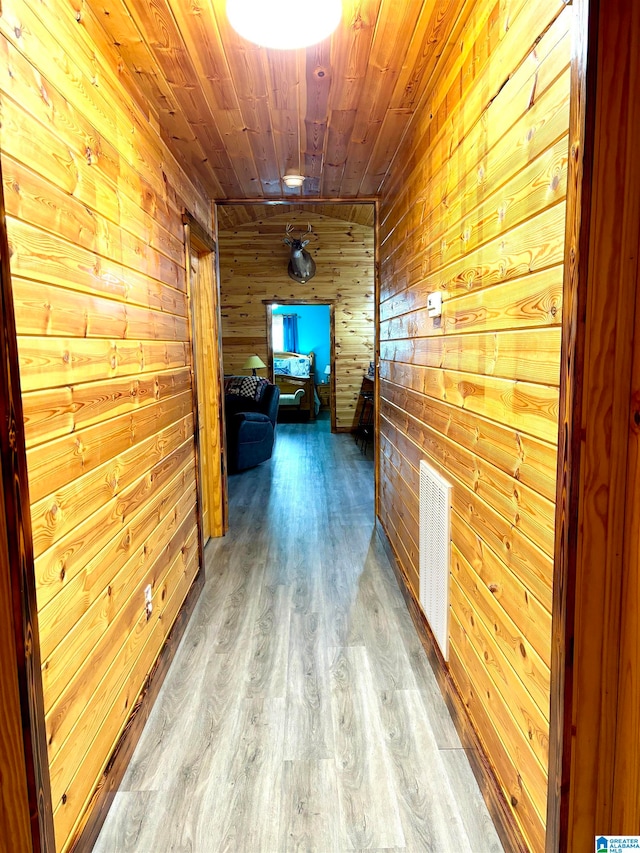 hallway with hardwood / wood-style floors, wooden walls, and wood ceiling