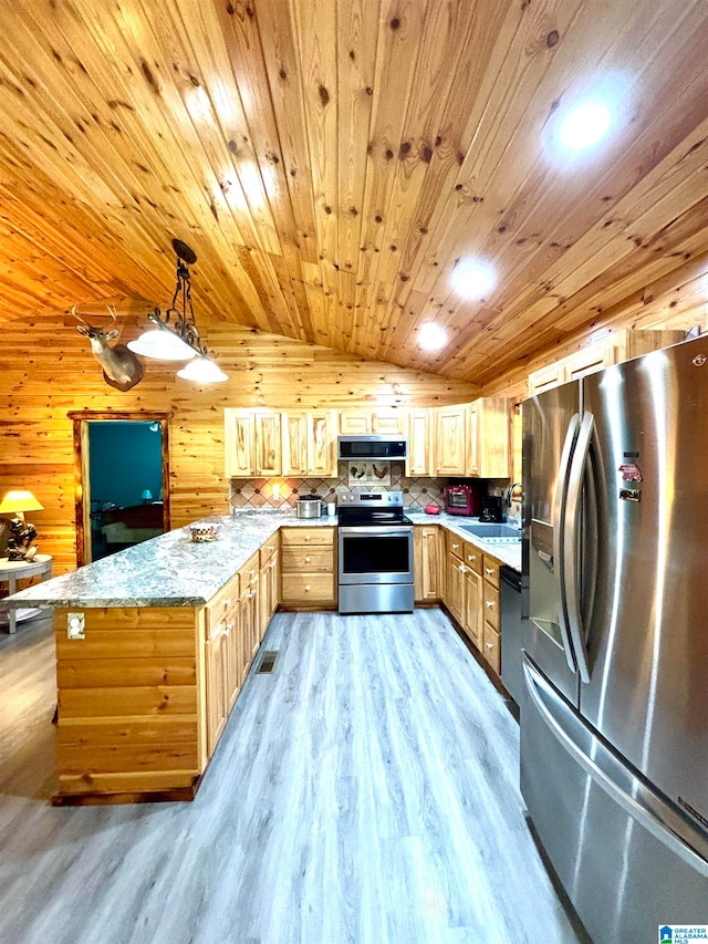 kitchen featuring light stone counters, stainless steel appliances, light hardwood / wood-style floors, hanging light fixtures, and wood walls