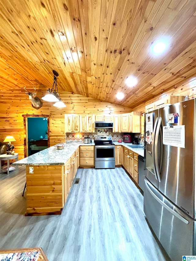 kitchen featuring appliances with stainless steel finishes, vaulted ceiling, light hardwood / wood-style flooring, hanging light fixtures, and wood walls