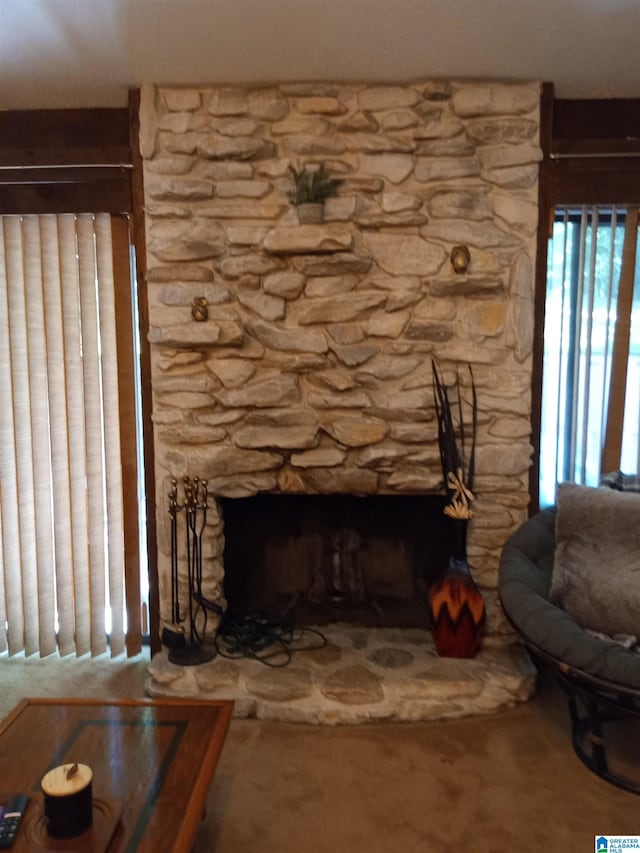 interior details featuring a stone fireplace and carpet