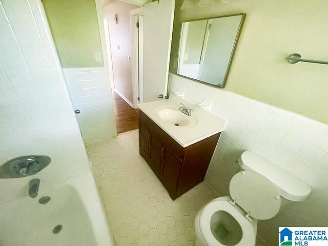 full bathroom featuring toilet, vanity, tile patterned floors, and tile walls