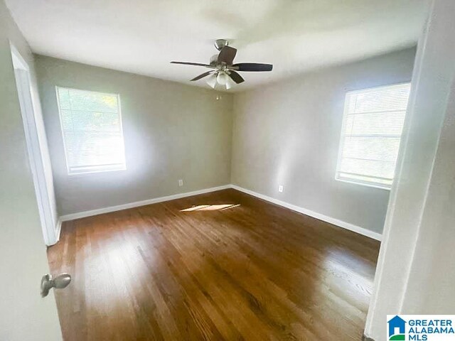 unfurnished room with ceiling fan, dark wood-type flooring, and a wealth of natural light