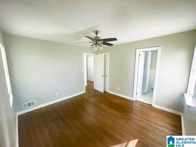 unfurnished bedroom featuring ceiling fan, dark wood-type flooring, and connected bathroom