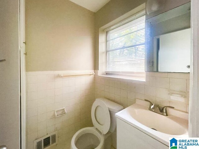 bathroom with vanity, tile walls, and toilet