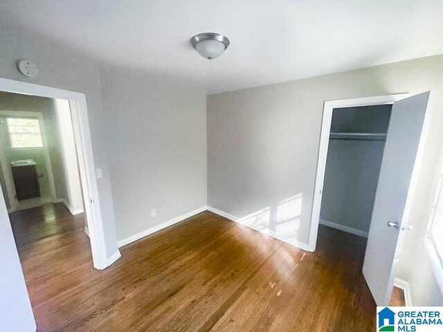 unfurnished bedroom with a closet and dark hardwood / wood-style floors