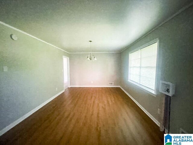 unfurnished dining area featuring dark hardwood / wood-style flooring, crown molding, and a notable chandelier