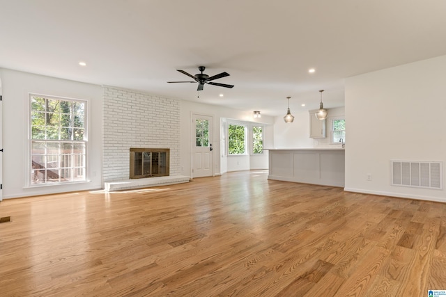 unfurnished living room with light hardwood / wood-style floors, a brick fireplace, and ceiling fan