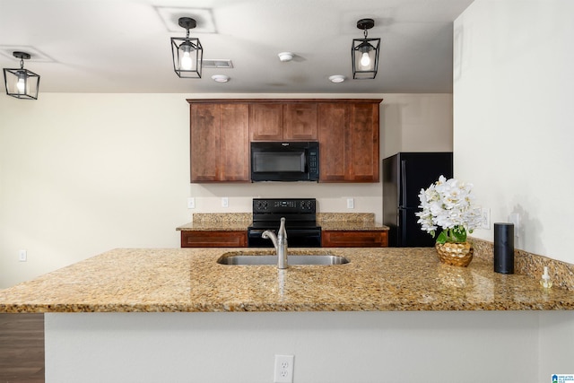 kitchen with kitchen peninsula, light stone countertops, sink, black appliances, and hardwood / wood-style flooring