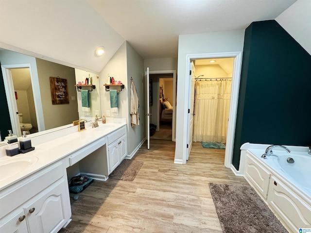 bathroom with vanity, hardwood / wood-style flooring, and vaulted ceiling