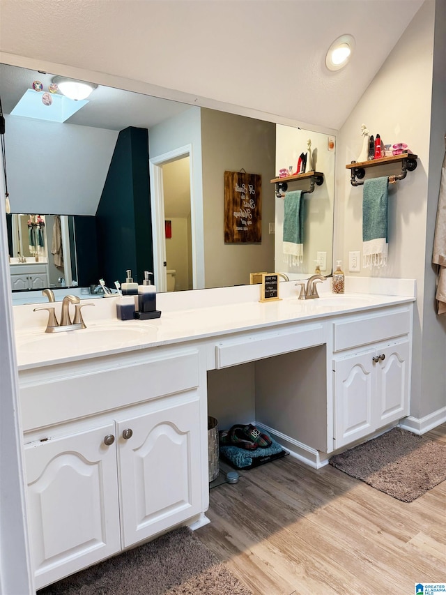 bathroom with hardwood / wood-style floors, vanity, and vaulted ceiling