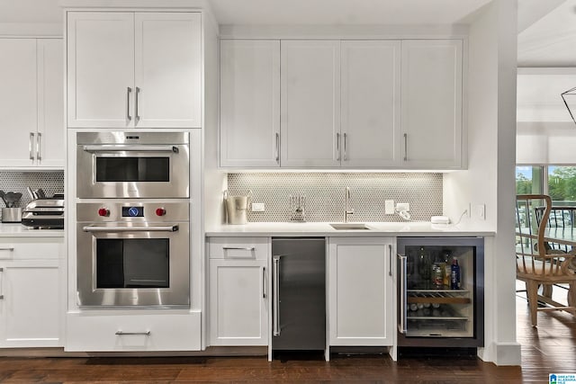 kitchen with dark wood-type flooring, white cabinets, stainless steel appliances, and sink