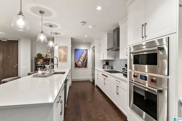 kitchen featuring white cabinets, wall chimney exhaust hood, dark hardwood / wood-style flooring, and a kitchen island with sink