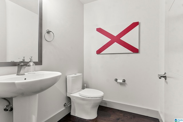 bathroom with toilet, wood-type flooring, and sink