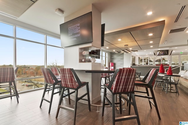 kitchen with a breakfast bar area, floor to ceiling windows, hardwood / wood-style floors, and an inviting chandelier