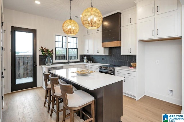 kitchen with premium range hood, white cabinetry, a kitchen island, and electric stove