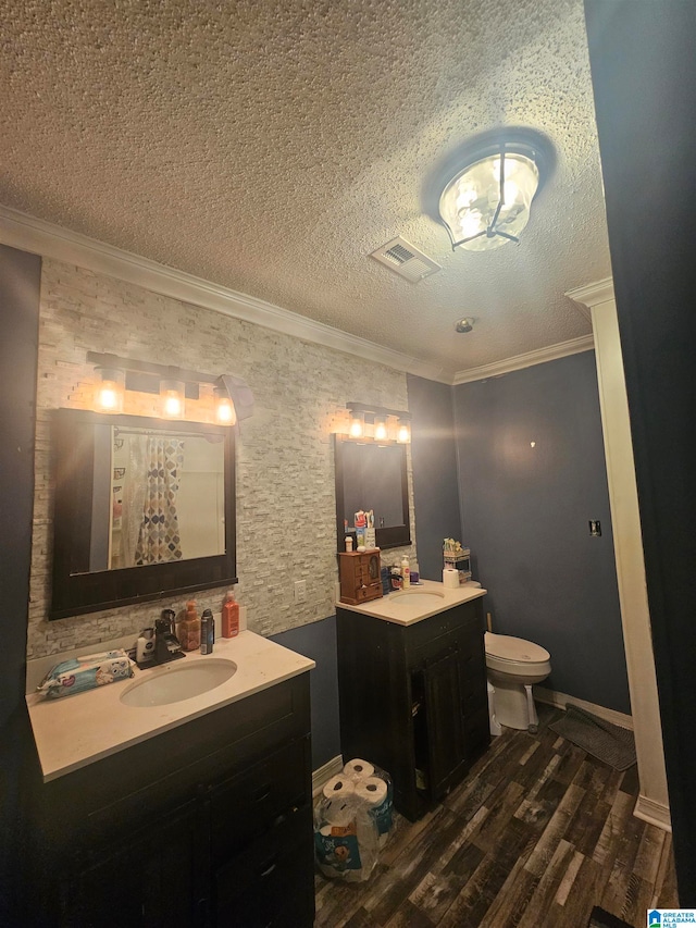 bathroom with crown molding, a textured ceiling, toilet, vanity, and hardwood / wood-style flooring