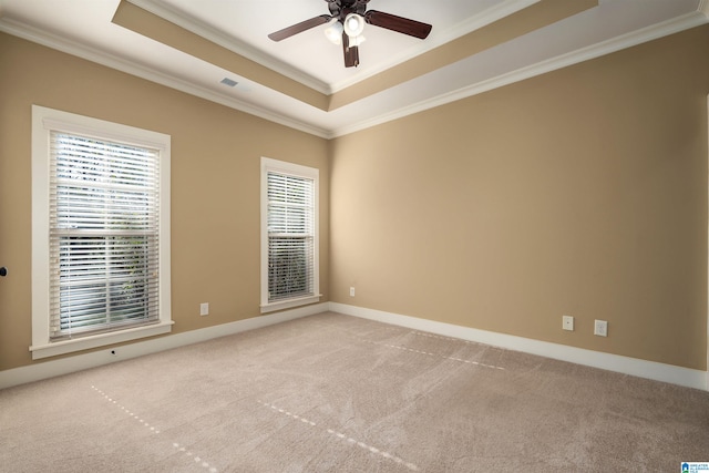 carpeted spare room with a raised ceiling, crown molding, and ceiling fan