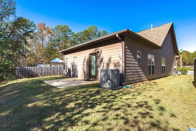 rear view of house featuring central air condition unit, a patio area, and a lawn