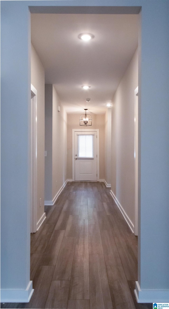 hallway with dark hardwood / wood-style floors and a chandelier