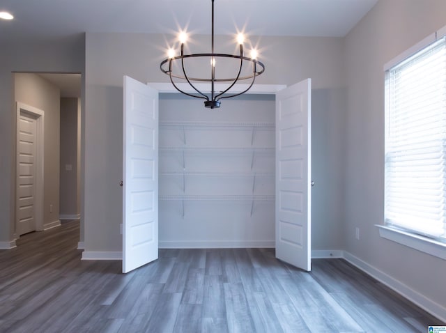 unfurnished dining area with a notable chandelier and dark hardwood / wood-style flooring