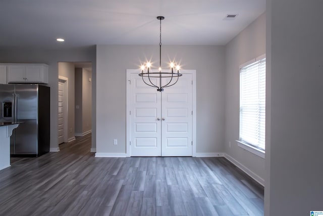 unfurnished dining area featuring plenty of natural light, dark hardwood / wood-style floors, and an inviting chandelier