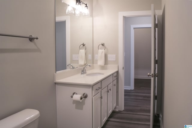 bathroom with hardwood / wood-style floors, vanity, and toilet