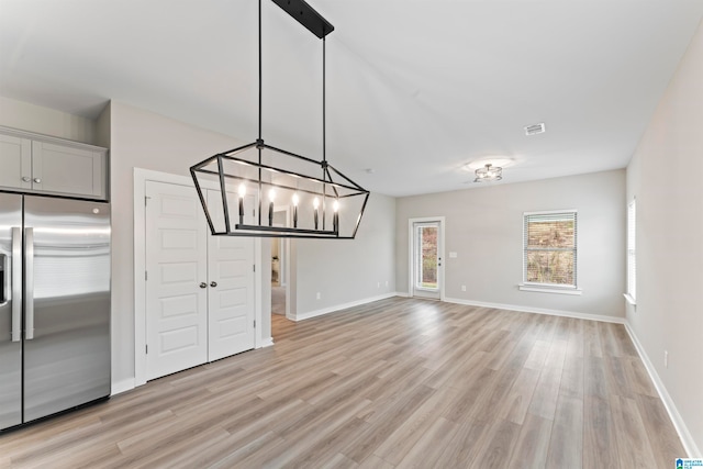 unfurnished dining area featuring light hardwood / wood-style flooring and a notable chandelier