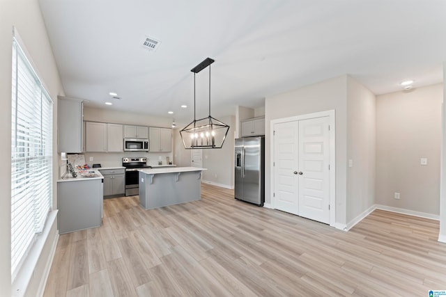 kitchen featuring pendant lighting, plenty of natural light, gray cabinetry, and stainless steel appliances