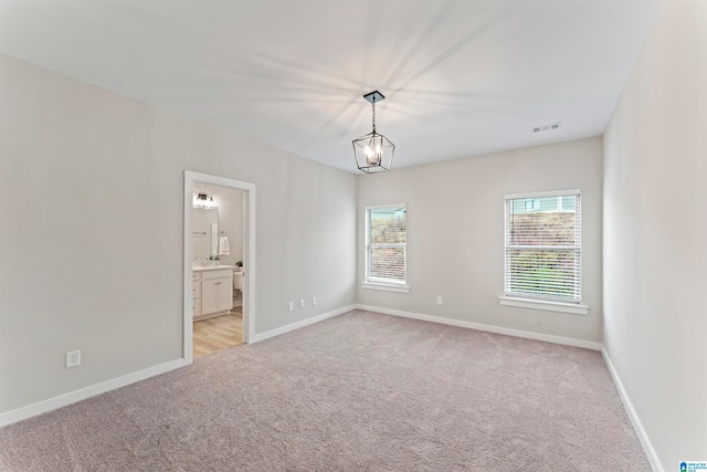 empty room with light colored carpet and a chandelier