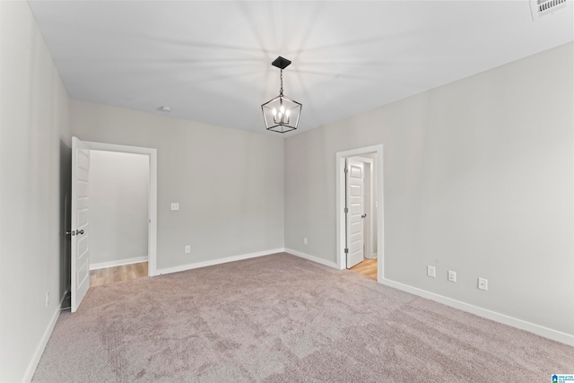 empty room with light carpet and a chandelier