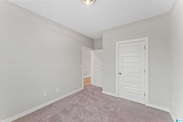 unfurnished bedroom with light colored carpet and a closet