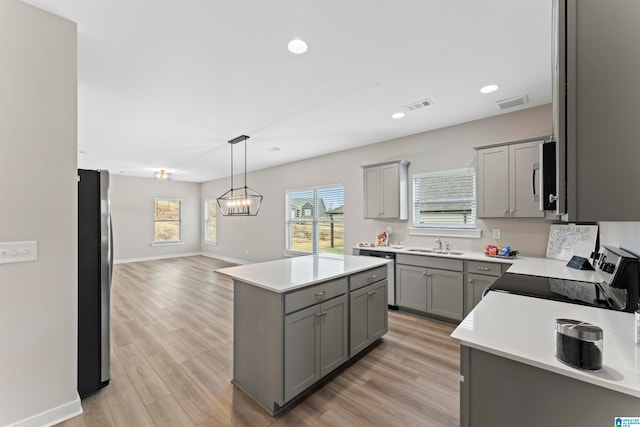 kitchen featuring a center island, light hardwood / wood-style flooring, gray cabinets, a notable chandelier, and stainless steel appliances