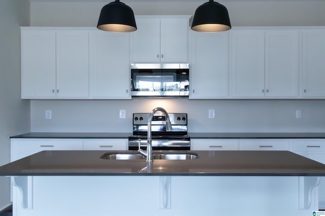 kitchen featuring stainless steel appliances, sink, pendant lighting, a center island with sink, and white cabinetry