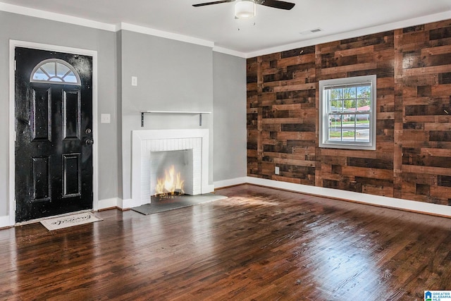 unfurnished living room featuring dark hardwood / wood-style floors, a brick fireplace, ceiling fan, and wooden walls