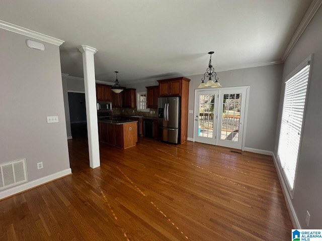 kitchen with appliances with stainless steel finishes, ornamental molding, a center island, dark hardwood / wood-style floors, and hanging light fixtures