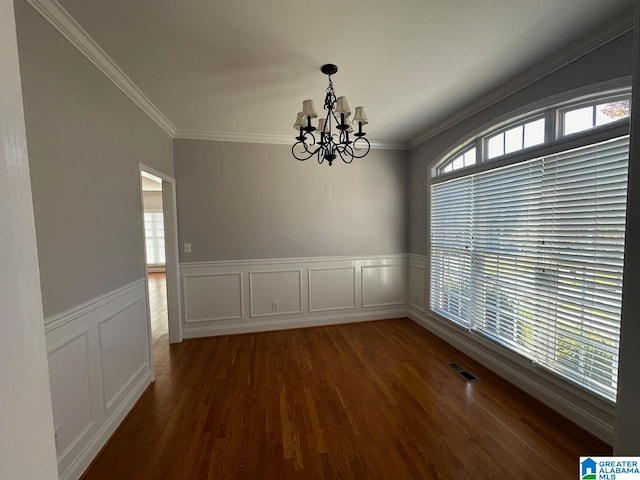 spare room featuring dark wood-type flooring, ornamental molding, and a notable chandelier