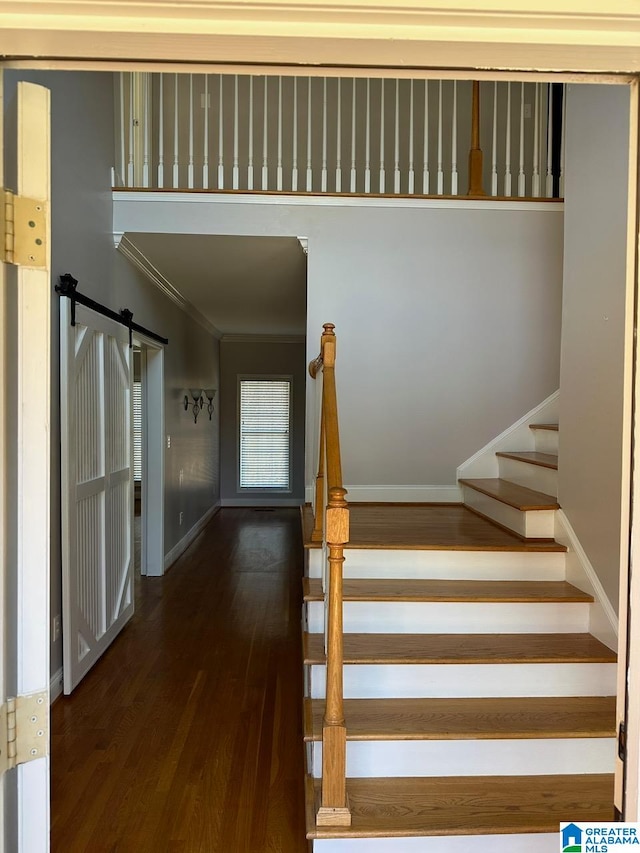 staircase featuring hardwood / wood-style flooring, a barn door, and crown molding