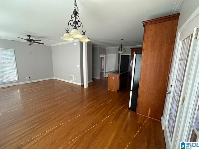 kitchen with ceiling fan, hanging light fixtures, dark wood-type flooring, refrigerator, and ornamental molding