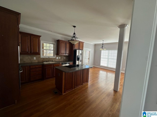 kitchen with appliances with stainless steel finishes, dark hardwood / wood-style flooring, decorative columns, sink, and a kitchen island