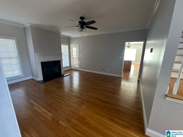 unfurnished living room featuring dark wood-type flooring, ceiling fan with notable chandelier, and ornamental molding