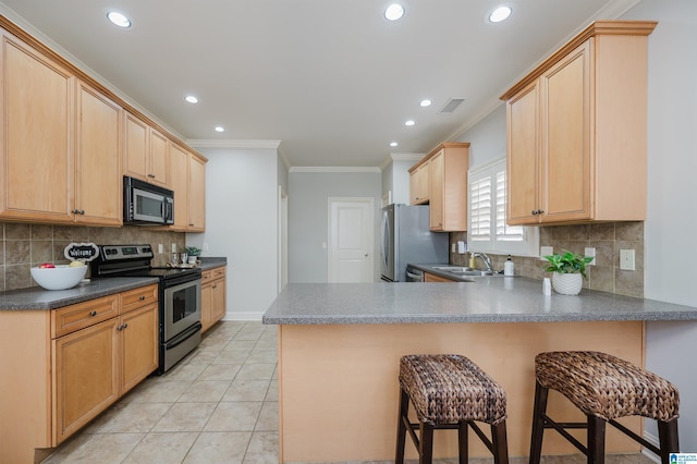 kitchen featuring a breakfast bar, sink, stainless steel appliances, kitchen peninsula, and light brown cabinetry