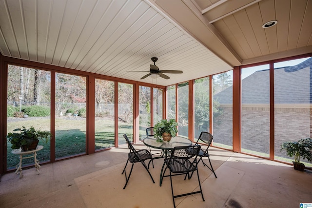 unfurnished sunroom featuring beamed ceiling and ceiling fan