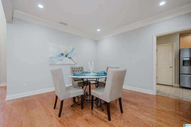 dining area featuring ornamental molding and light hardwood / wood-style flooring