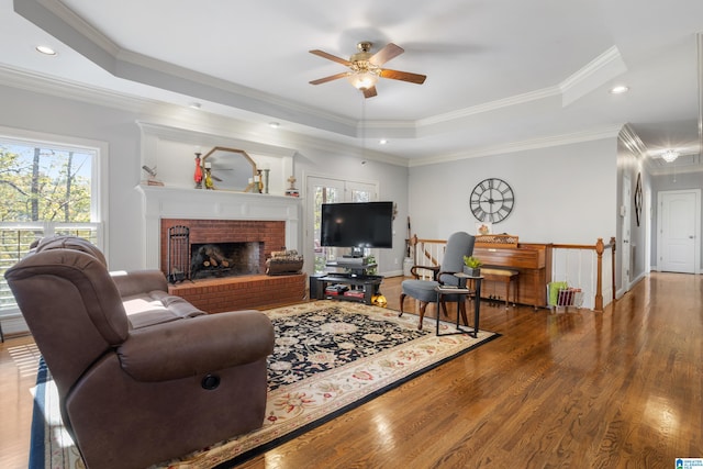 living room with a tray ceiling, crown molding, ceiling fan, and hardwood / wood-style flooring