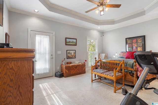 bedroom with light carpet, a tray ceiling, ceiling fan, and ornamental molding