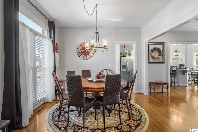 dining area with light hardwood / wood-style floors and an inviting chandelier