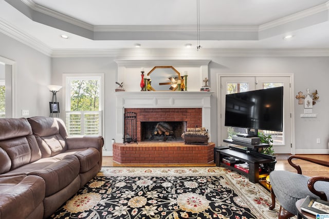 living room featuring a fireplace, a healthy amount of sunlight, light wood-type flooring, and crown molding